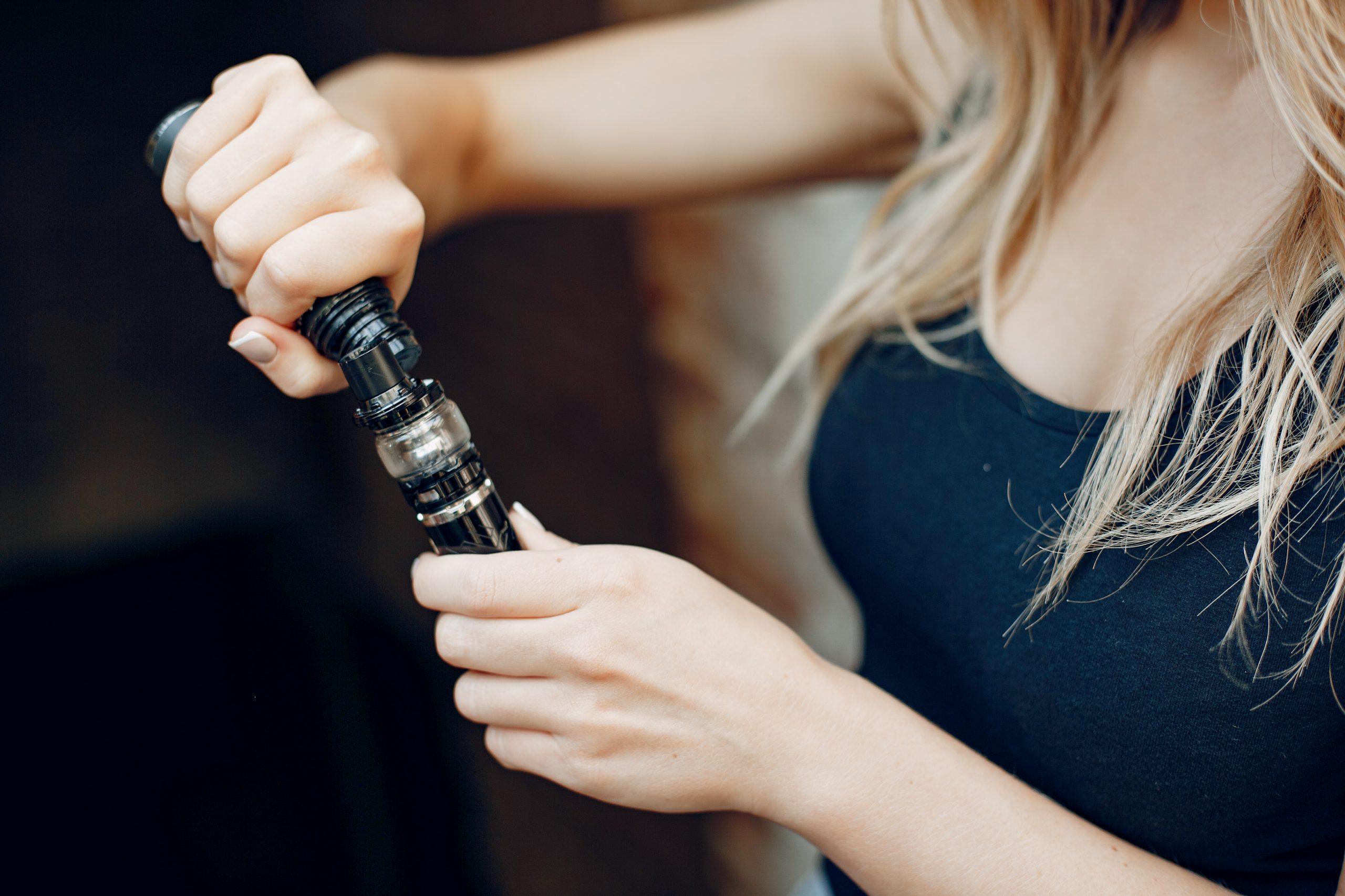 Stylish girl in a city. Lady use the electronic cigarette. Woman in a red jacket.